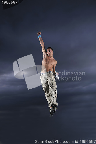 Image of young man dancing and jumping  on top of the building 