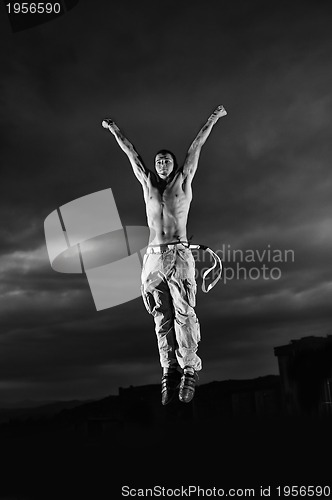 Image of young man dancing and jumping  on top of the building 