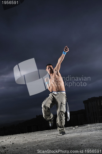 Image of young man dancing and jumping  on top of the building 