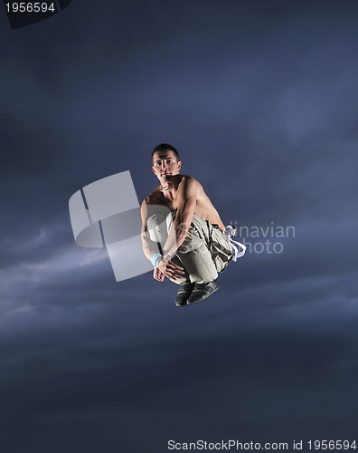 Image of young man dancing and jumping  on top of the building 