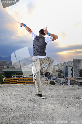 Image of young man jumping in air outdoor at night ready to party