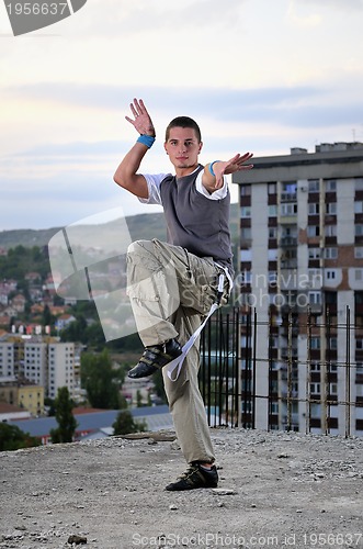 Image of young man jumping in air outdoor at night ready to party