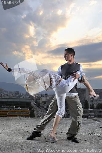 Image of romantic urban couple dancing on top of the bulding 