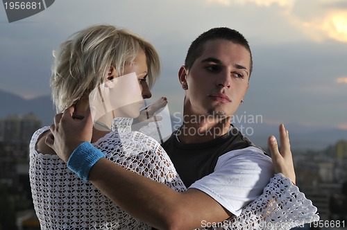 Image of romantic urban couple dancing on top of the bulding 