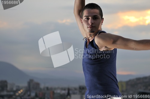 Image of young man jumping in air outdoor at night ready for party