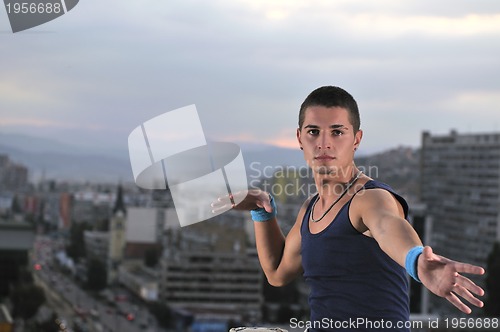 Image of young man jumping in air outdoor at night ready for party