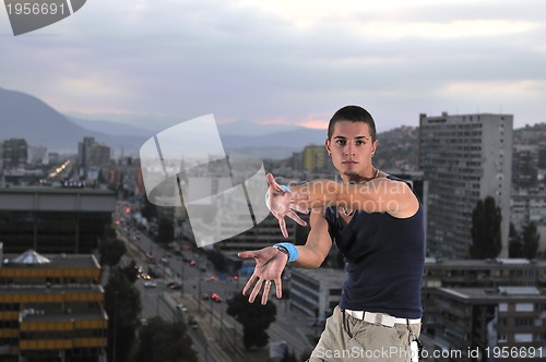 Image of young man jumping in air outdoor at night ready for party