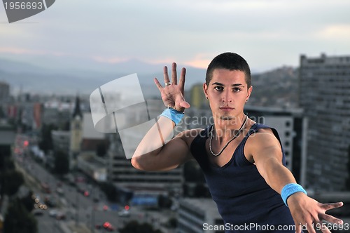Image of young man jumping in air outdoor at night ready for party