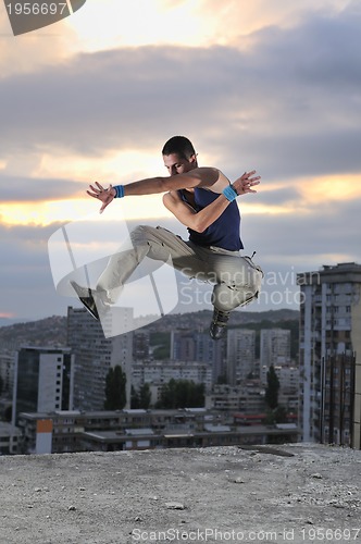 Image of young man jumping in air outdoor at night ready for party