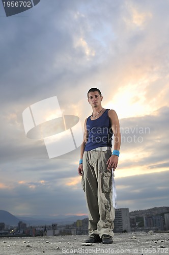 Image of young man dancing and jumping  on top of the building 