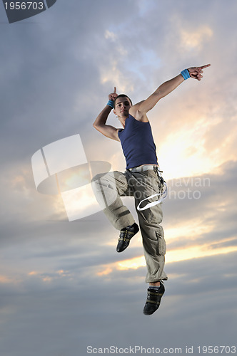 Image of young man dancing and jumping  on top of the building 