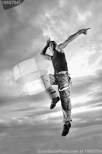 Image of young man dancing and jumping  on top of the building 
