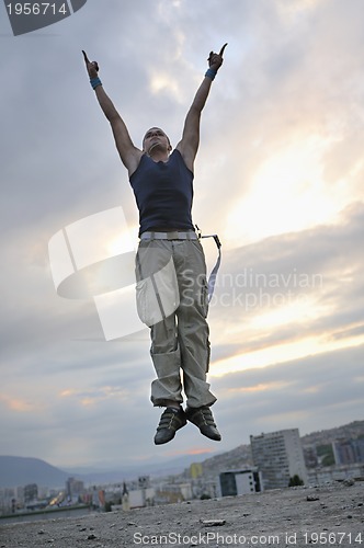 Image of young man jumping in air outdoor at night ready for party