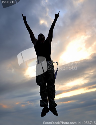 Image of young man jumping in air outdoor at night ready for party