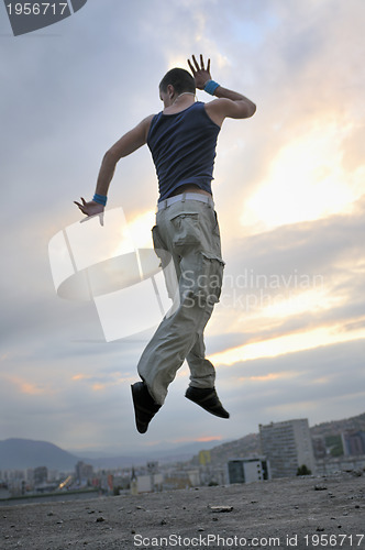 Image of young man dancing and jumping  on top of the building 