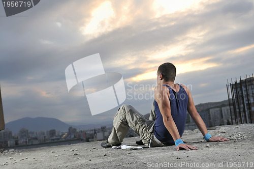 Image of young man dancing and jumping  on top of the building 