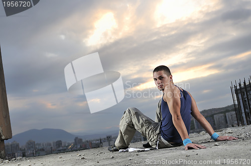 Image of young man dancing and jumping  on top of the building 