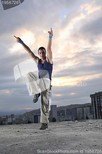 Image of young man dancing and jumping  on top of the building 