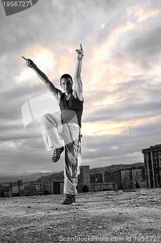 Image of young man dancing and jumping  on top of the building 