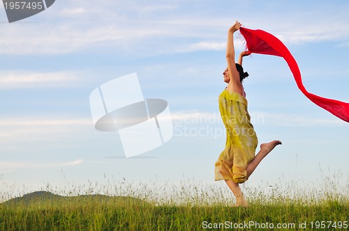 Image of beautiful woman with red scarf on meadow