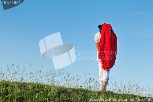 Image of beautiful woman with red scarf on meadow