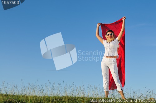 Image of beautiful woman with red scarf on meadow