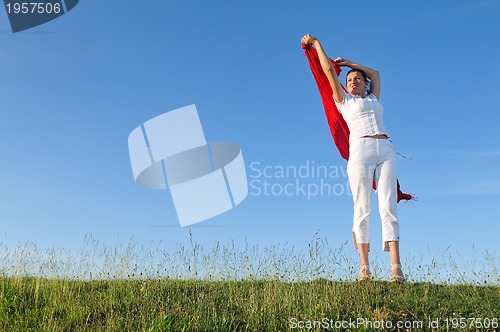 Image of beautiful woman with red scarf on meadow