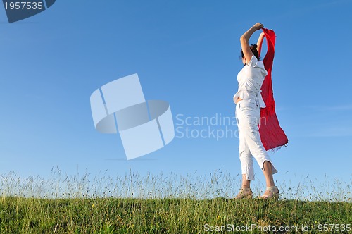 Image of beautiful woman with red scarf on meadow