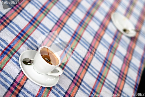 Image of Cup of coffee on a colorful tablecloth