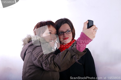 Image of Tow ladies taking picture with mobile phone 