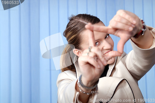 Image of portrait of young business woman creates a frame with her hands