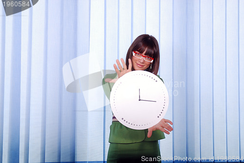 Image of .a pretty business woman hiding behind a clock