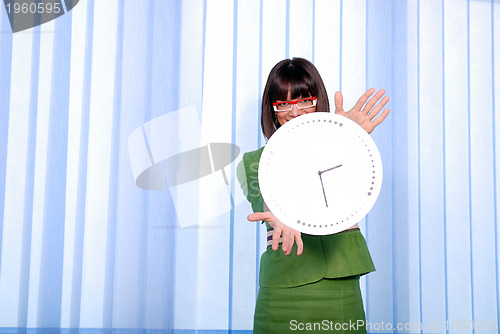 Image of .a pretty business woman hiding behind a clock