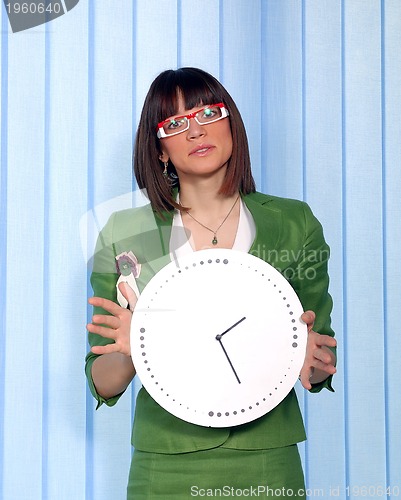 Image of .a pretty business woman hiding behind a clock