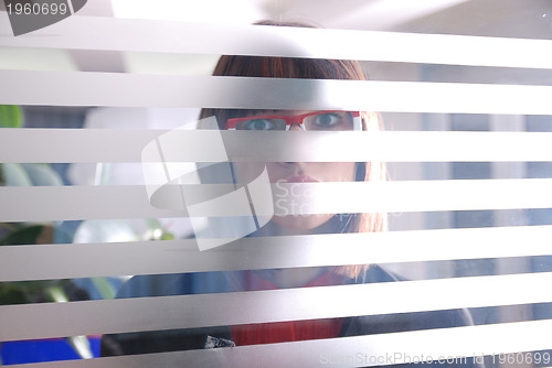 Image of young businesswoman looking trought transparent wall