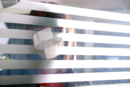 Image of young businesswoman looking trought transparent wall