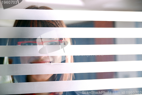 Image of young businesswoman looking trought transparent wall