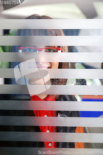 Image of young businesswoman looking trought transparent wall