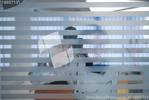 Image of young businesswoman looking trought transparent wall