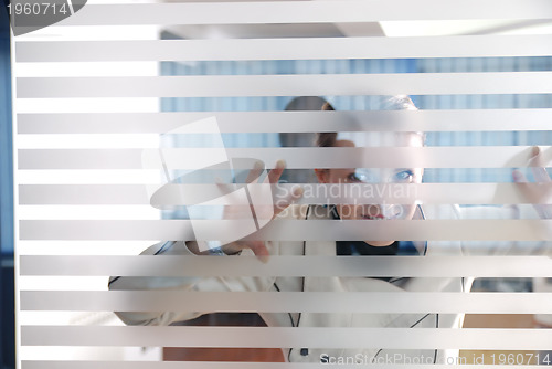 Image of young businesswoman looking trought transparent wall