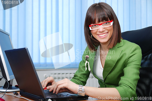 Image of Smiling young businesswoman working on a laptop in the office.