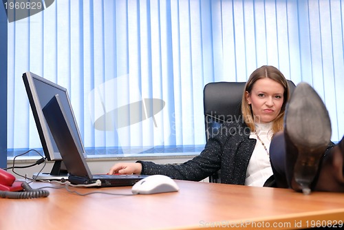 Image of .business woman relaxing with her feet on the desk
