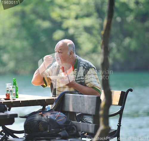 Image of senior man eat desser at outdoor restaurant