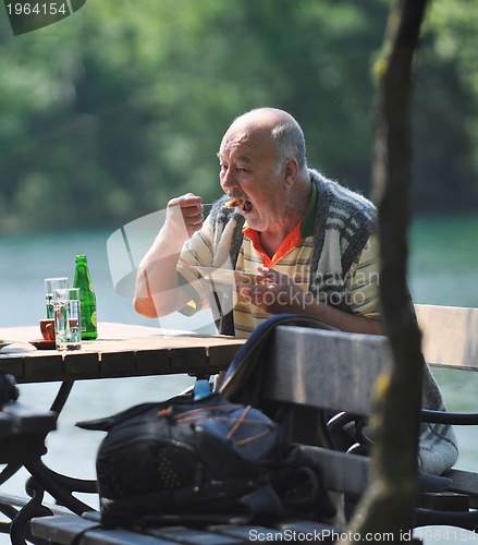 Image of senior man eat desser at outdoor restaurant