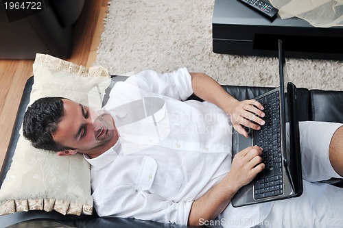 Image of Portrait of a relaxed young guy using laptop at home
