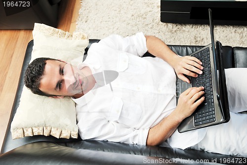 Image of Portrait of a relaxed young guy using laptop at home
