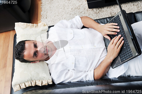 Image of Portrait of a relaxed young guy using laptop at home