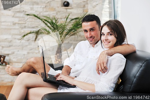 Image of joyful couple relax and work on laptop computer at modern home