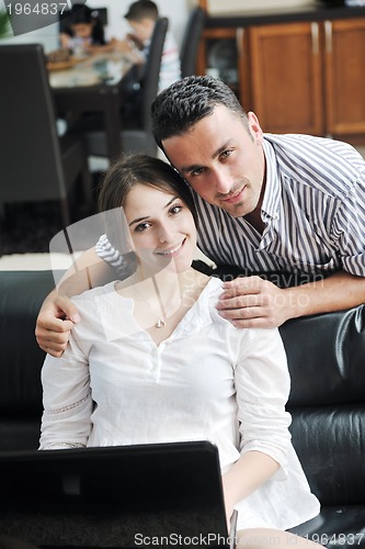 Image of joyful couple relax and work on laptop computer at modern home