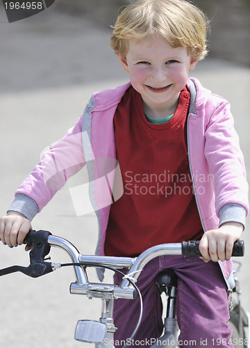 Image of cute little girl driving bicyle at sunny day